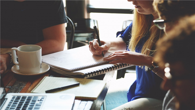 Woman sitting at a table writing on a notepad